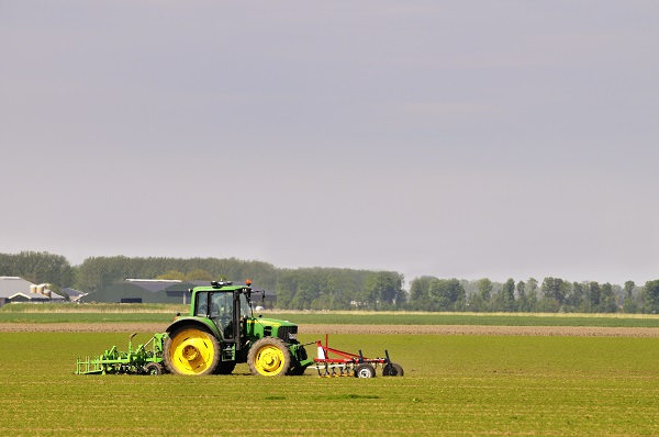 Dronten, The Netherlands - May 14, 2012: John Deere 6430 tractor working the fields near the town of Dronten in Flevoland in spring. A farmer is driving the tractor.