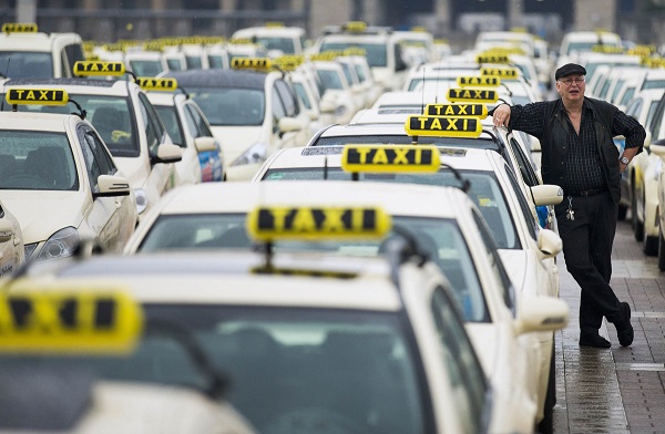 A taxi driver listens to speeches by his colleagues, during an Europe-wide protest of licensed taxi drivers against taxi hailing apps that are feared to flush unregulated private drivers into the market, in front of the Olympic stadium in Berlin. (Thomas Peter/Reuters)