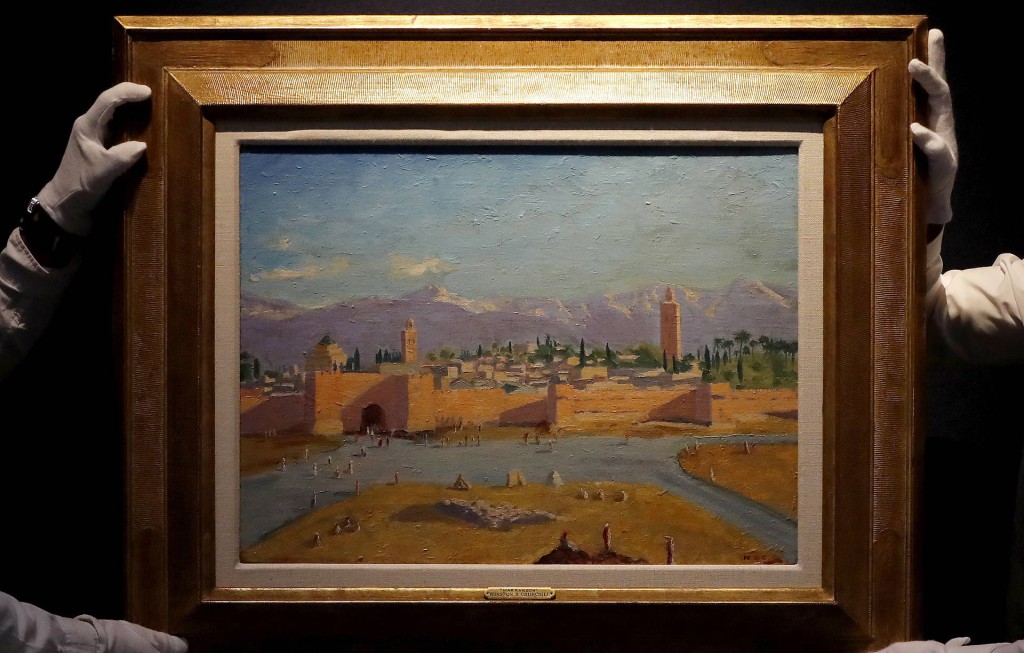 FILE - In this Wednesday, Feb. 17, 2021 file photo, Christie's employees adjust an oil on canvas painting by Sir Winston Churchill painted in Jan. 1943 called 'Tower of the Koutoubia Mosque' during an Art pre-sale photo call at Christie's auction house in London. The Moroccan landscape painted by Winston Churchill and owned by Angelina Jolie sold at auction on Monday March 1, 2021, for more than $11.5 million, smashing the previous record for a work by Britain’s World War II leader. (AP Photo/Frank Augstein, File)